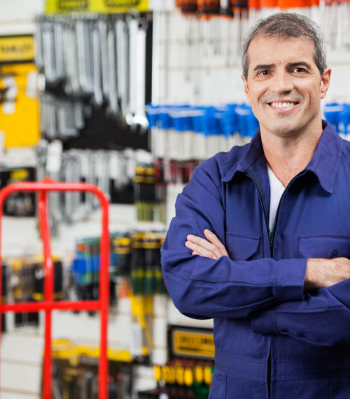 Portrait of confident worker with arms crossed standing in hardware shop
